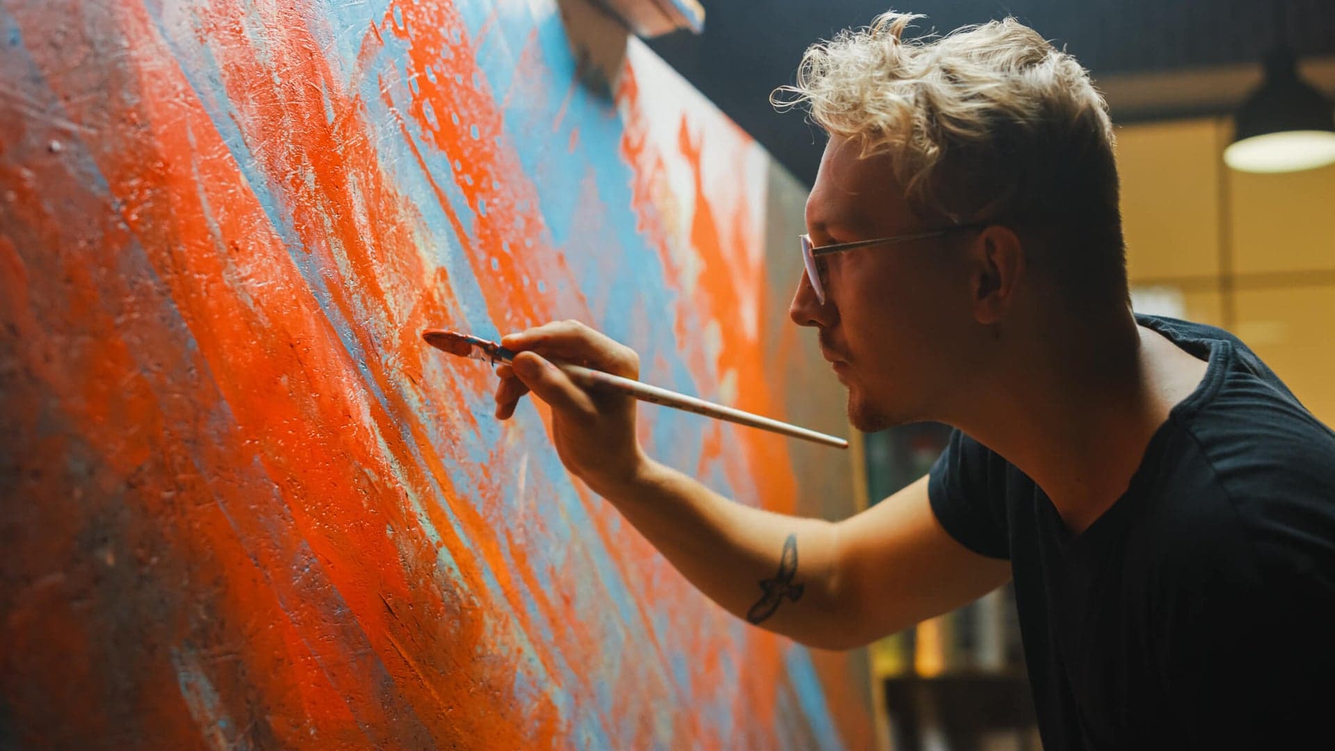 Artist painting a vibrant orange canvas
